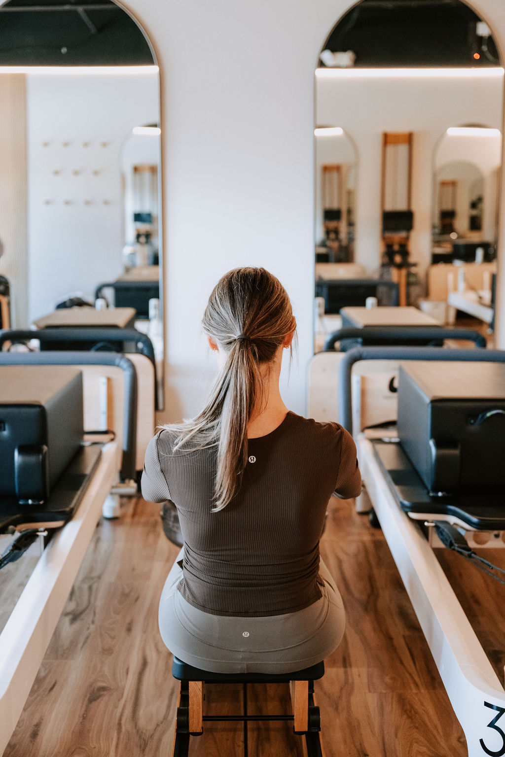 A client seated on the Reformer facing the arched mirrors
