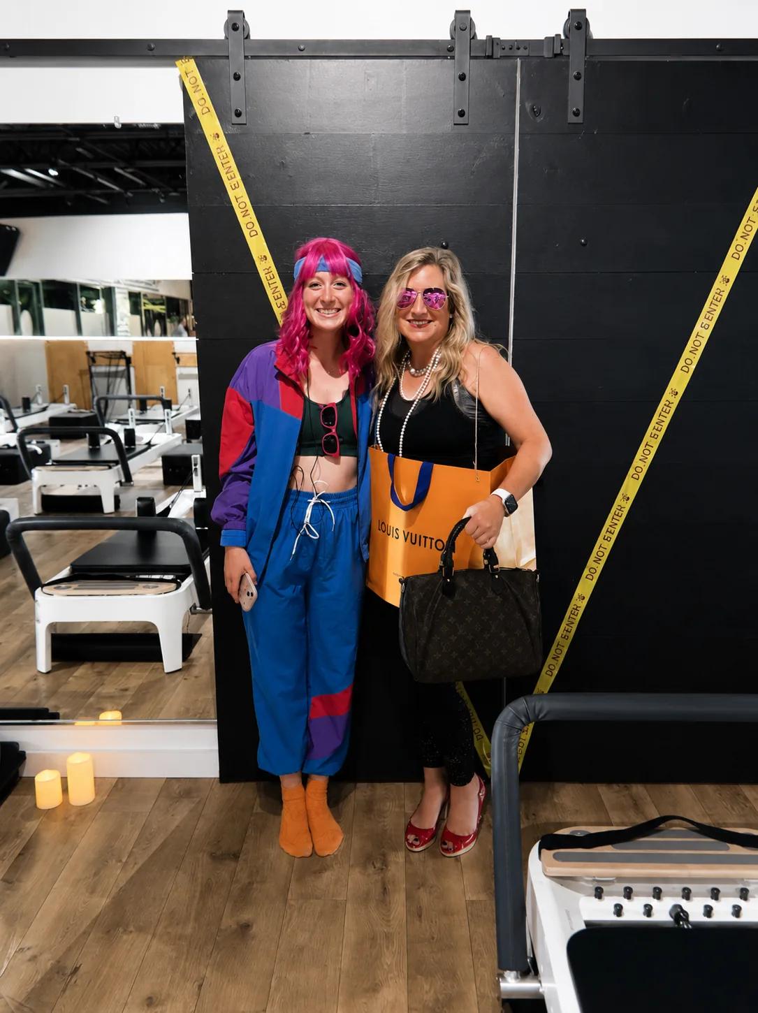 Two members dressed in colorful 80s outfits at a studio event