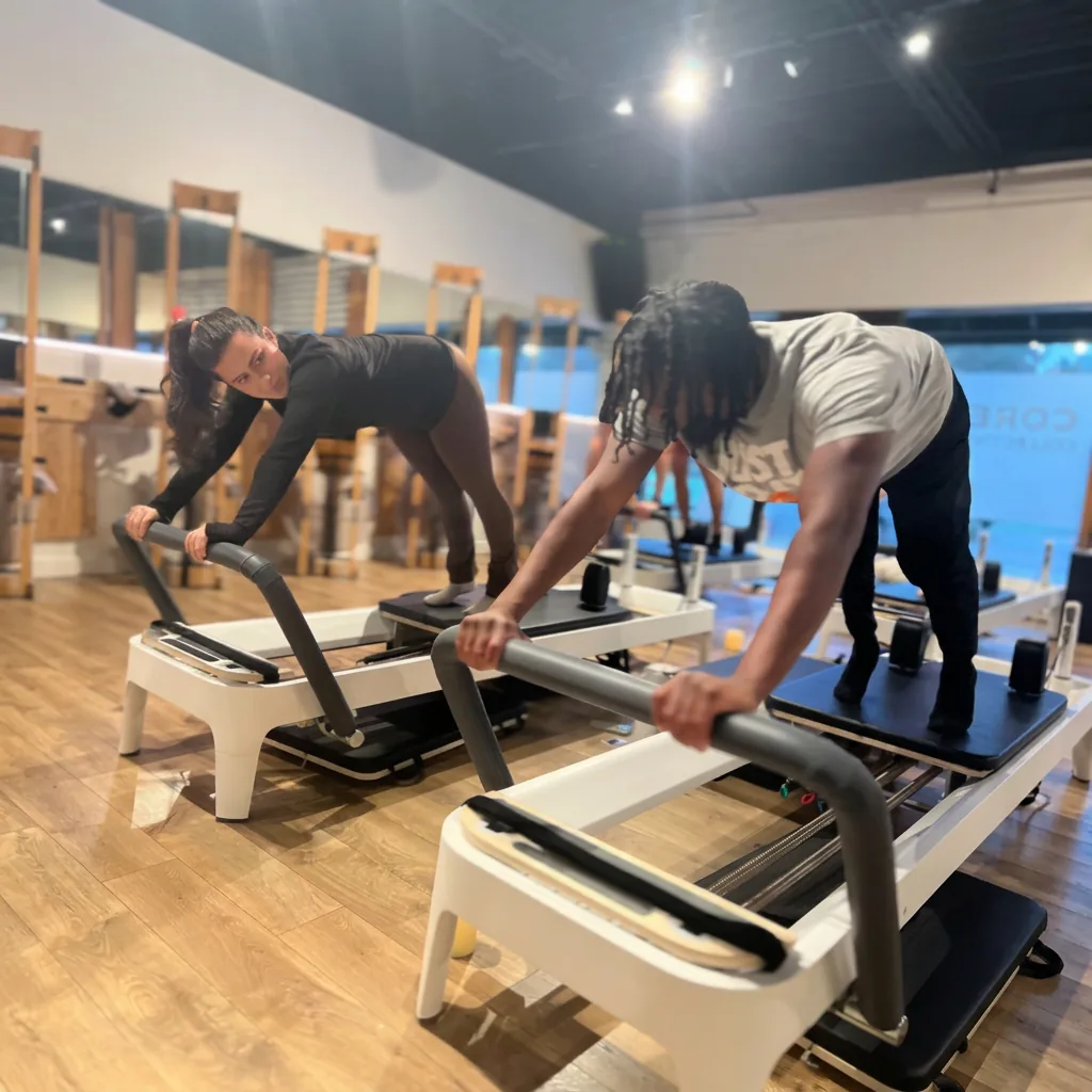 Two members in a plank position on Pilates reformers during a Core Collective class