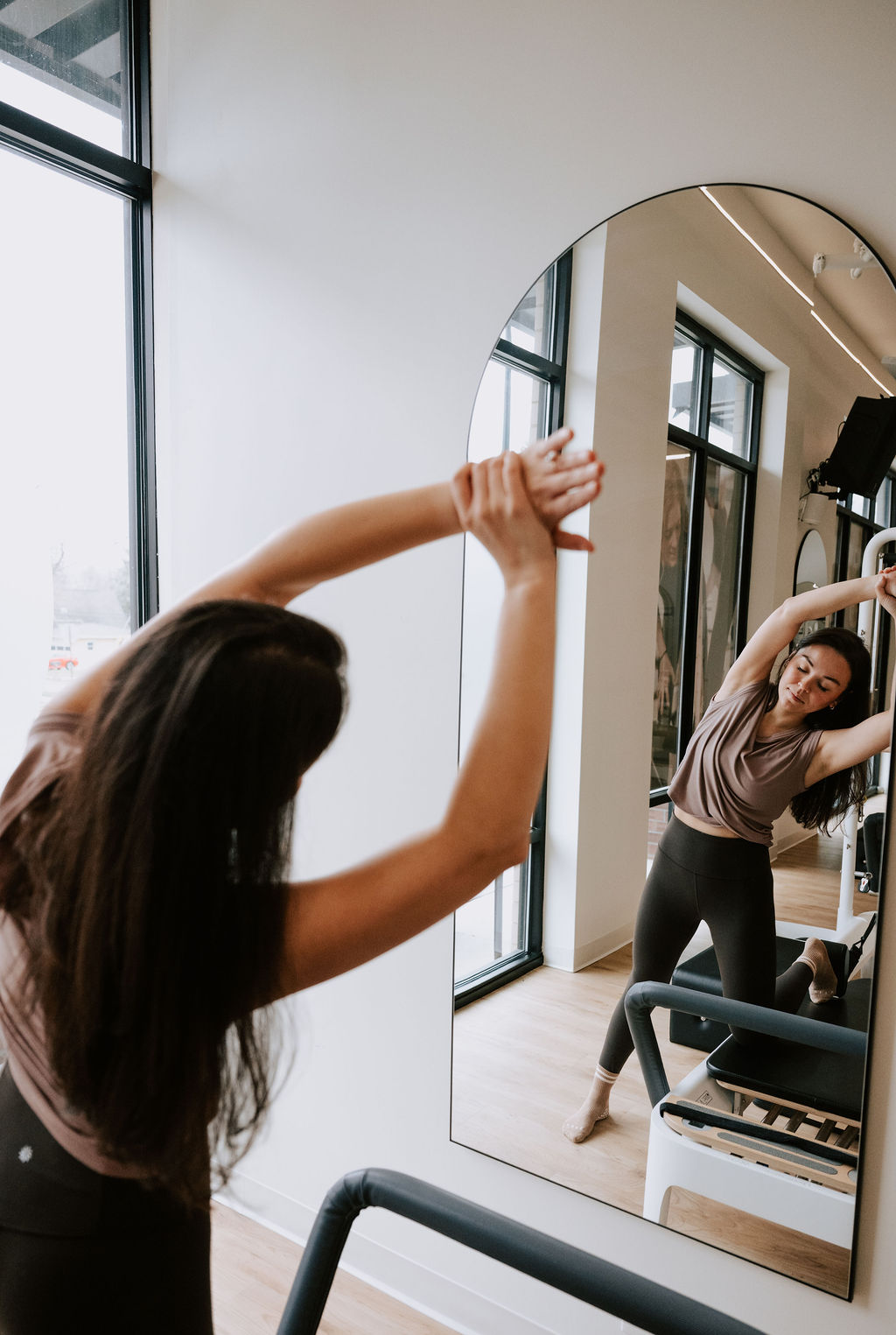 Member stretching side-body in front of the studio mirror
